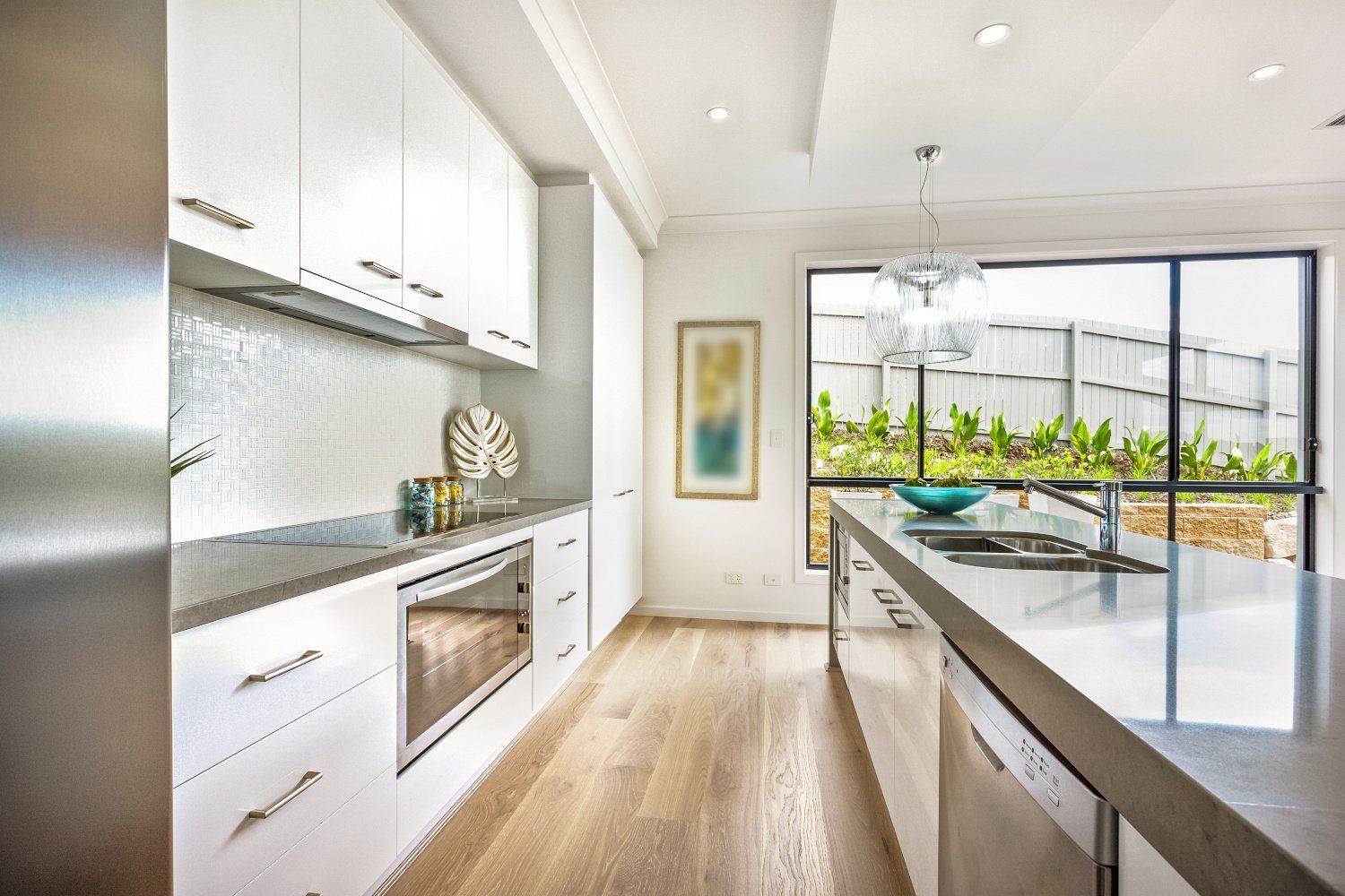 Modern galley kitchen with white cabinets, gray countertops and stainless appliances